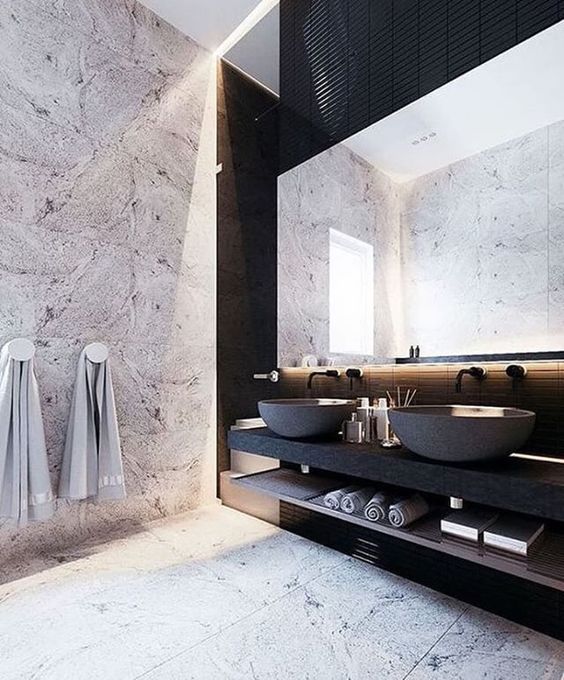 a stone wall, marble tiles and a matte black vanity and concrete sinks