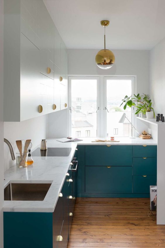 An eye catchy teal and white kitchen with brass touches looks chic and very inviting