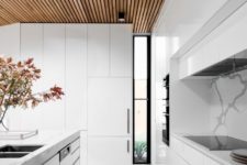 13 a modern all-white kitchen with a marble backsplash and a wooden ceiling