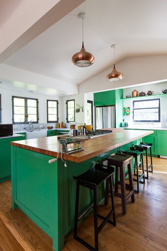 a bold green kitchen is made calmer with neutral countertops and brass touches