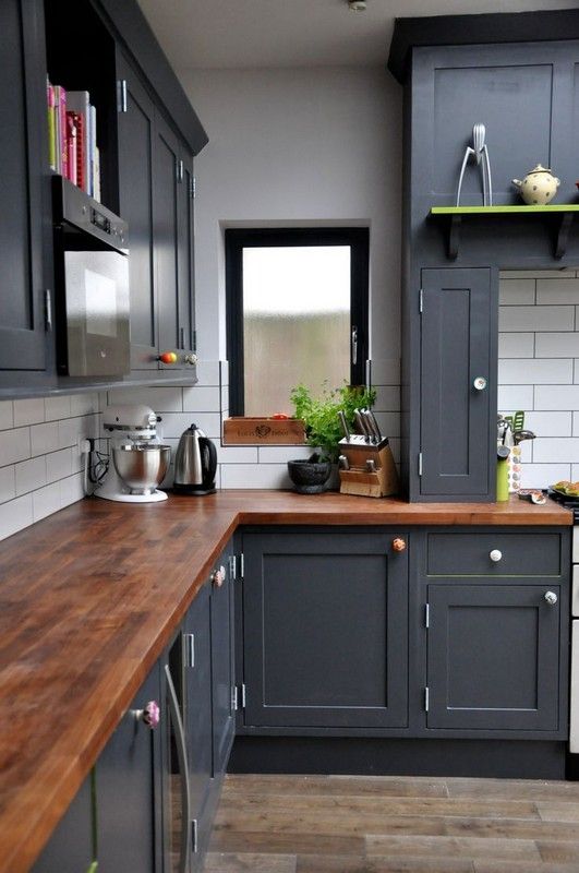 A graphite grey kitchen with warm colored wooden tabletops looks vintage and chic