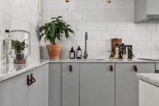 14 dove grey cabinets, white tiles that cover the whole walls and industrial pendant lamps for a stylish Scandinavian space