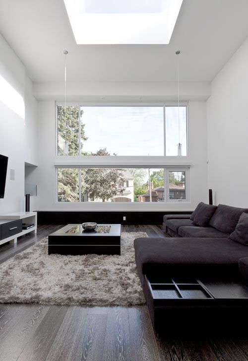 a laconic modern living room accentuated with dark floors and furniture and a fluffy rug
