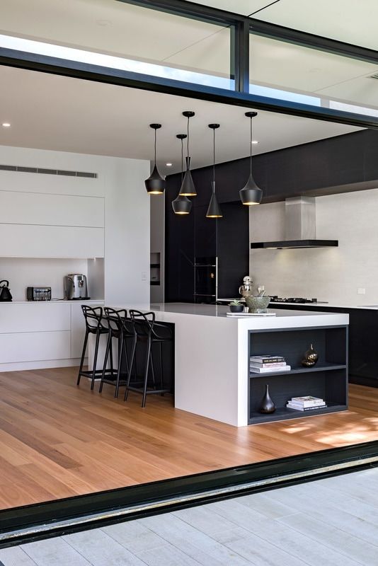 a modern black and white space with sleek cabinets and eye-catchy pendant lamps over the kitchen island