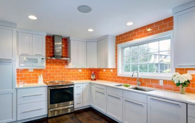 a bold orange tile backsplash extended on the walls gives color to the space