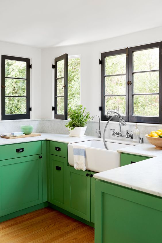 a farmhouse kitchen is added impact with bold sage green color of the cabinets