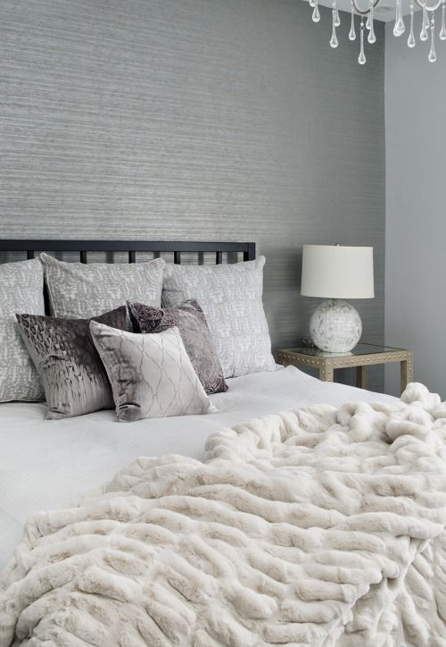 a grey bedroom with a white faux fur blanket that makes it more luxurious