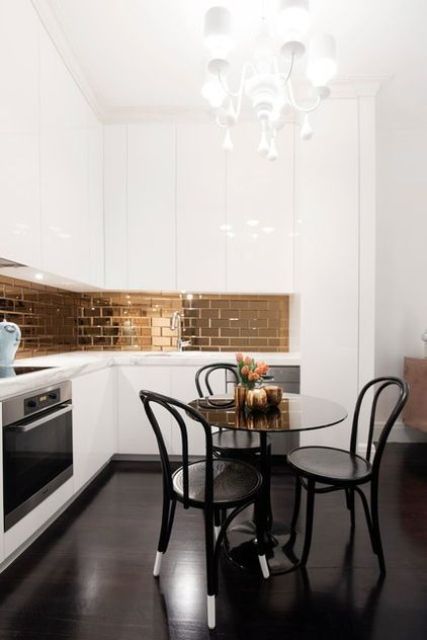 A modern elegant white kitchen with an L shape and a small dining space with a round table