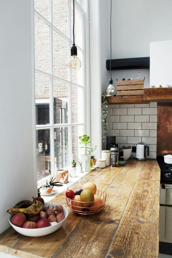 a reclaimed wood countertop adds coziness to the kitchen and contrasts the white tiles