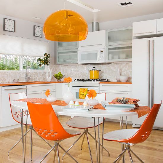 a contemporary kitchen with orange countertops, a lamp and chairs