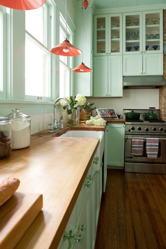 a mint green kitchen with coral lamps and natural wood countertops for a vintage feel