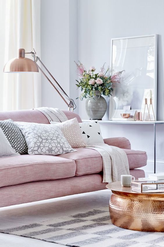 a pink sofa is a perfect piece for a feminine living room, and a copper table and lamp complete the look