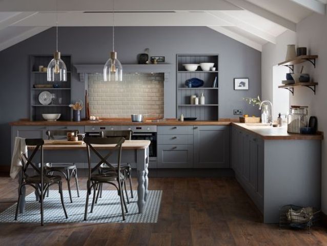 a dark grey vintage kitchen with wooden countertops and a matching dining table, which doubles as a kitchen island