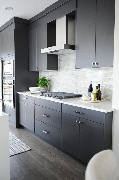 a dark grey kitchen with a light tile backsplash and white counters looks edgy and chic