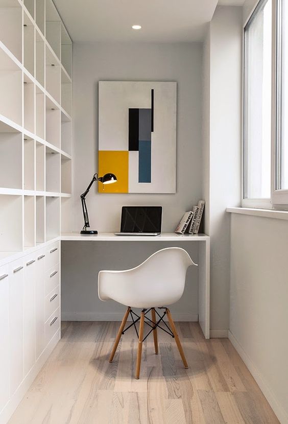 A minimalist home office with a large built in shelving unit and desk
