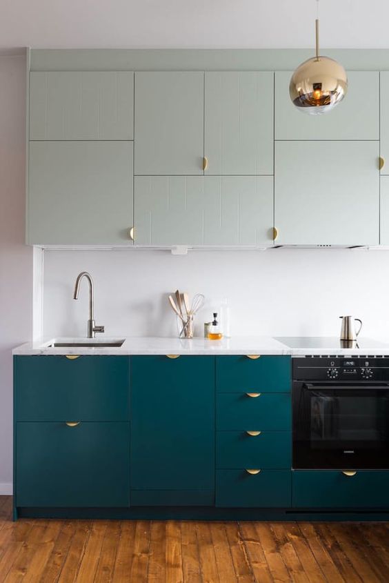 a modern kitchen with teal floor cabinets and very pale green ones above looks bold and very interesting