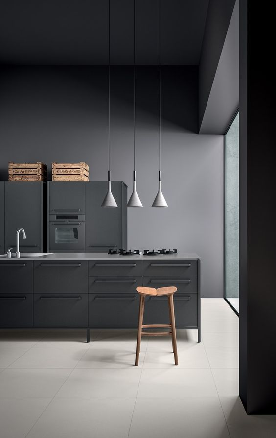 a grey metal industrial kitchen with crates and pendatn lamps done in concept of a moody space