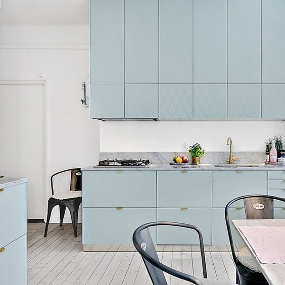 A beautiful aqua colored kitchen with lots of cabinets and whitewashed wooden floors for a light feeling