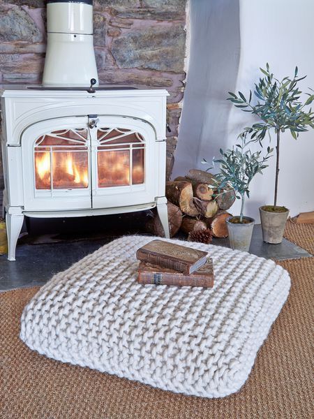a chunky knit floor pillow will also bring a cool warm touch to your bedroom, especially placed next to a hearth