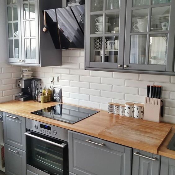 a vintage grey kitchen with wooden countertops and white subway tiles