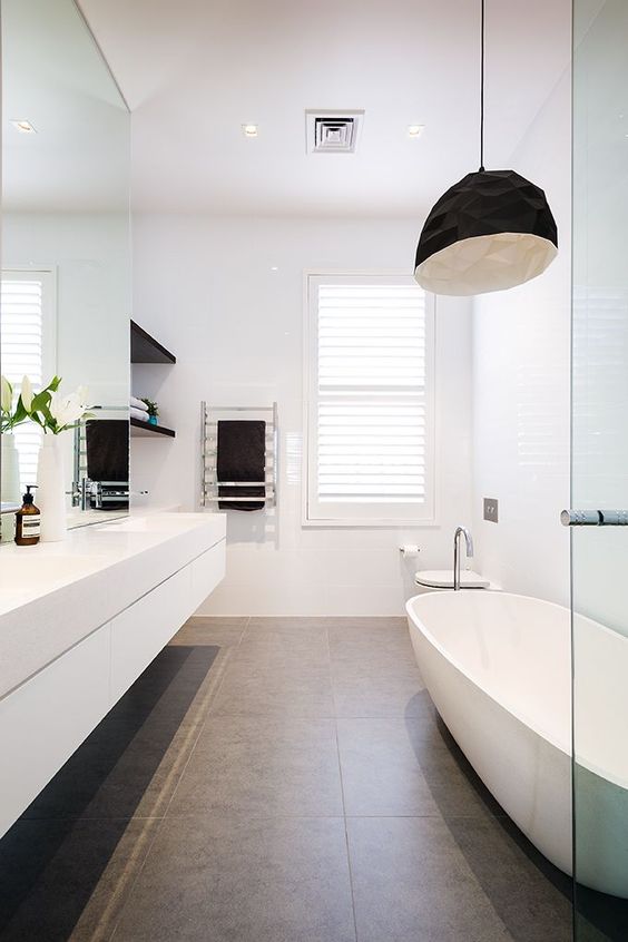 the bathroom is made more interesting with black shelves, a black faceted lamp and a large bathtub