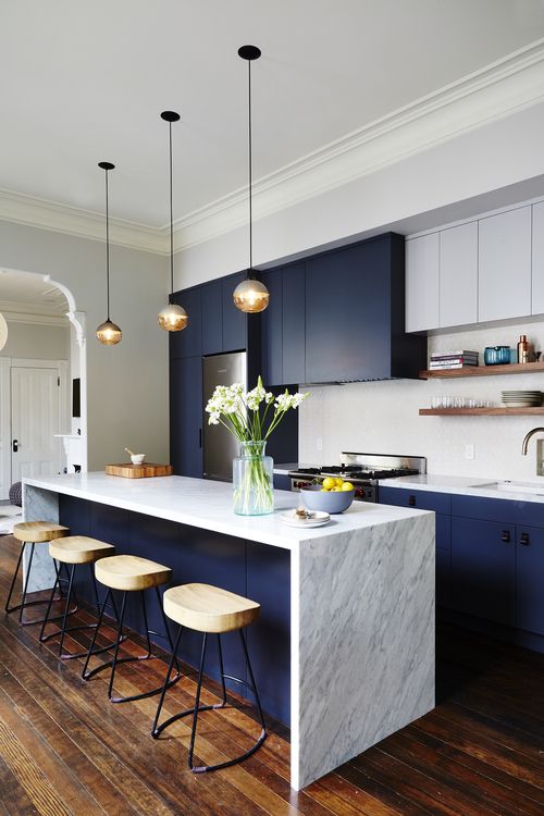 a chic modern space in cobalt blue and white looks very contrasting, a marble counter and wooden stools add interest