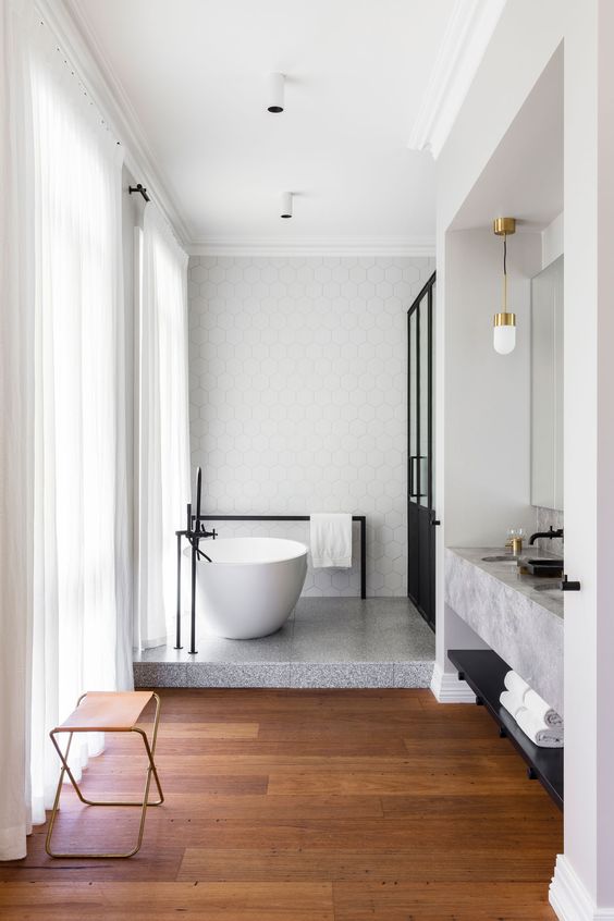 a chic space with geo tiles, grey bathtub floor, a concrete vanity, a black shower and wooden floors
