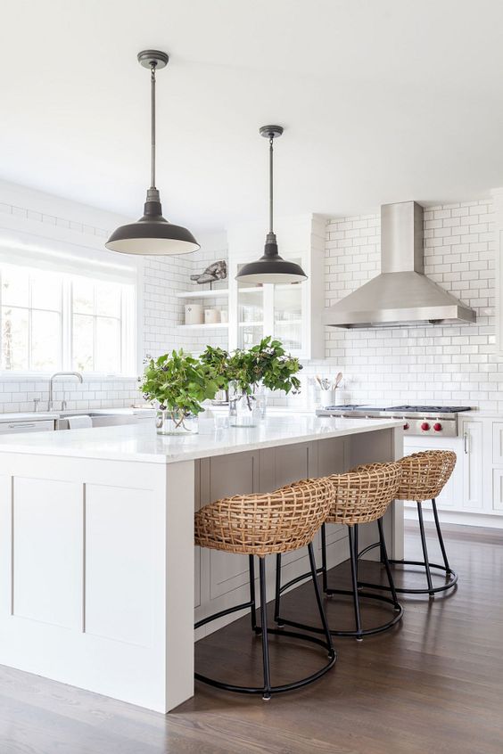 a chic white kitche with a functional kitchen island and woven stools