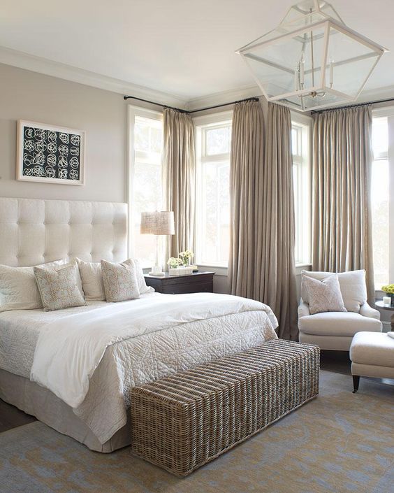 a neutral bedroom with a long wicker bench and storage space in one for a cozy feel