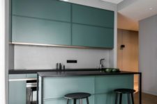 27 a modern dark green kitchen with black framing and a grey backsplash, small yet very stylish
