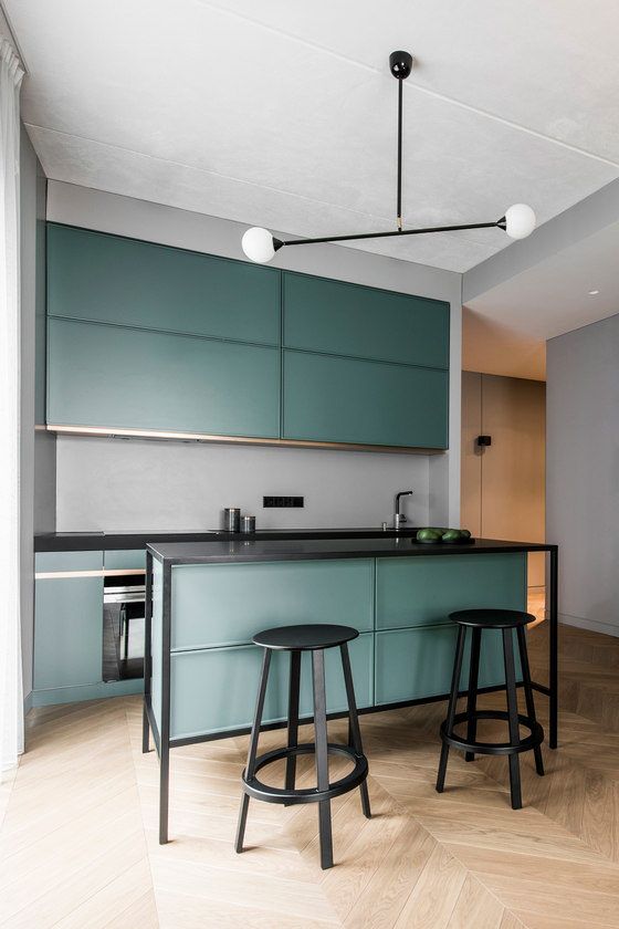 a modern dark green kitchen with black framing and a grey backsplash, small yet very stylish