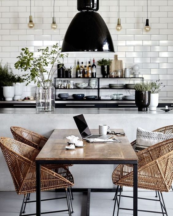 a modern monochrome kitchen with wicker chairs that soften the space and make it cozier