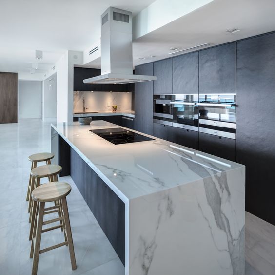 a minimalist dark kitchen with a gorgeous large white marble kitchen island for cooking and eating