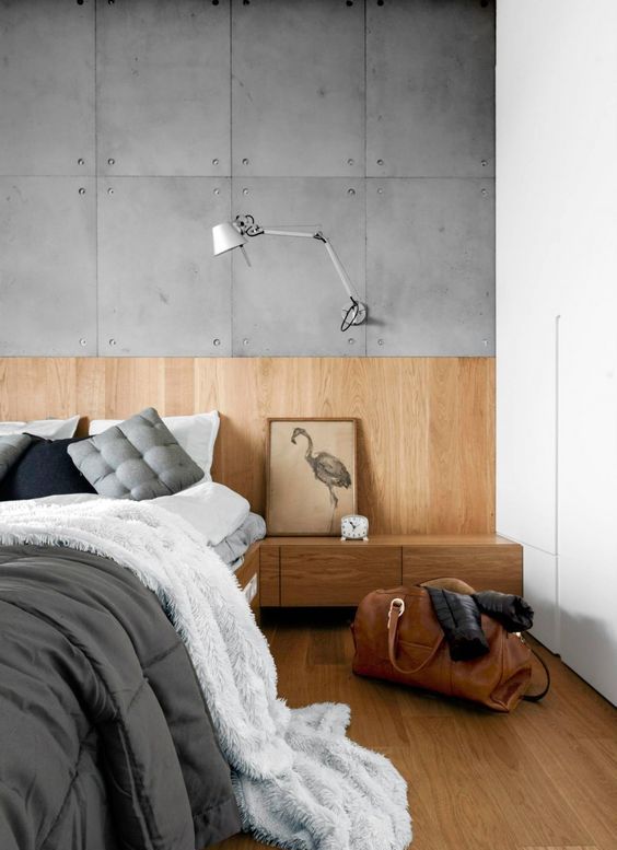 A modern light colored wood wall, platform bed and drawers cozy up the bedroom with concrete panels