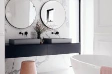 28 a modern space with white marble, a black vanity, a free-standing bathtub and concrete sinks looks chic