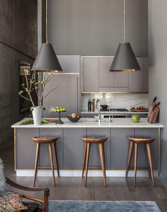 a modern small kitchen with matte grey cabinets, white marble counters and a backsplash and matching lamps