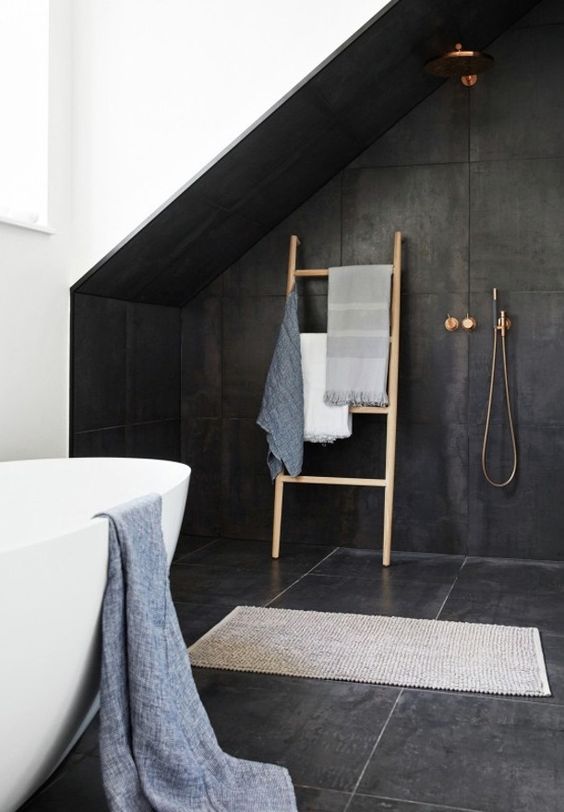 attic bathroom with attic accentuated with black tiles and some brass fixtures