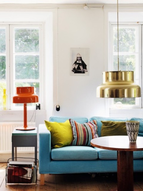 This colorful space with a blue sofa and colorful lamps is a part of a boho house in Sweden, though this style isn't traditional for Scandinavian countries