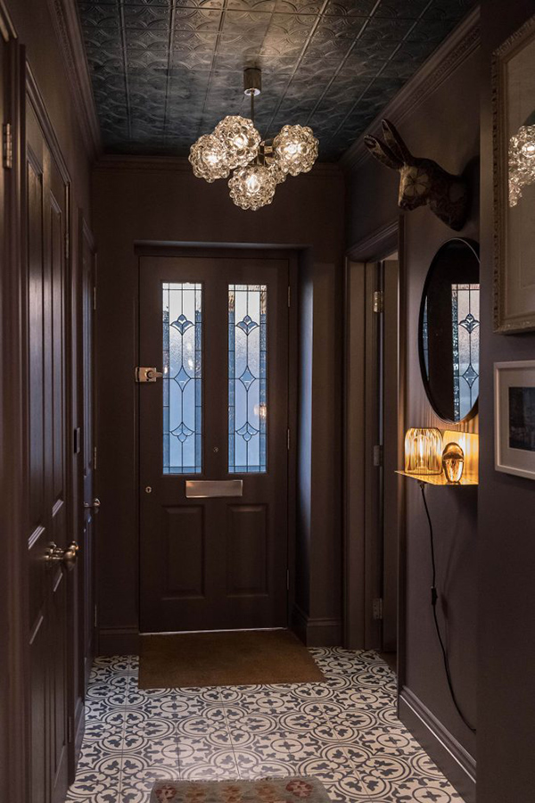 The entryway is done in dark shades, with a faux animal head and cool vintage lamps that hint on what's further