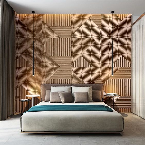 A modern space with a wood clad geometric wall, an upholstered bed and eye catchy lamps hanging from above
