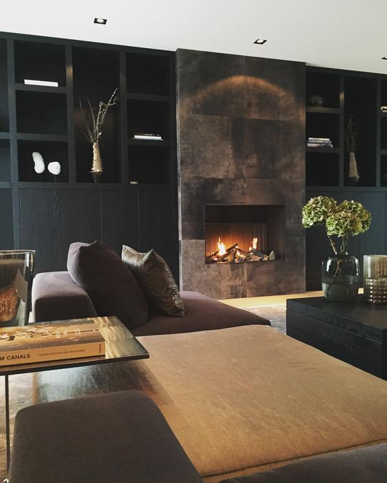 a refined moody living room with a built-in fireplace clad with dark metal looks wow