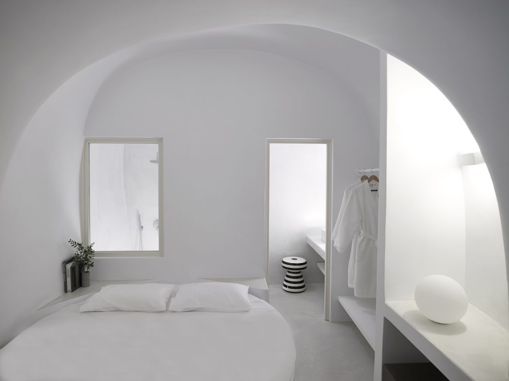 One of the bedrooms with a round bed, some built in shelves and a bathroom enclosed