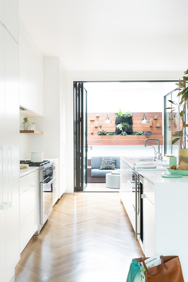 The kitchen features all-white decor and an entrance to the terrace