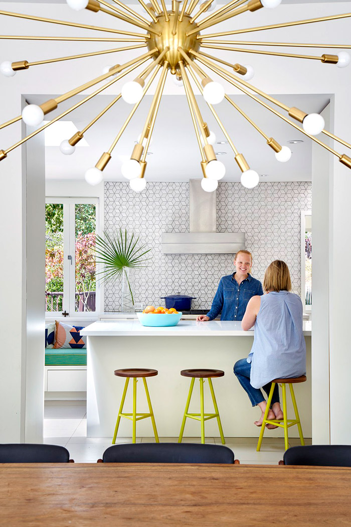 The kitchen features geometric tiles, colorful stools and is bright and open
