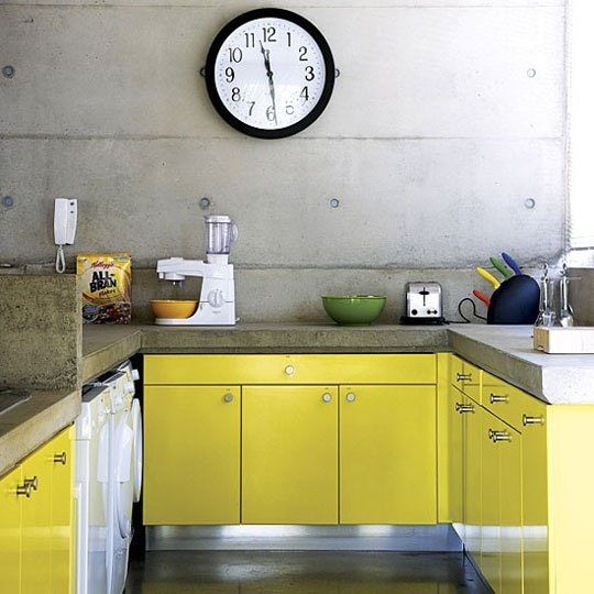 an industrial kitchen with lemon yellow cabinets, concrete walls and concrete countertops