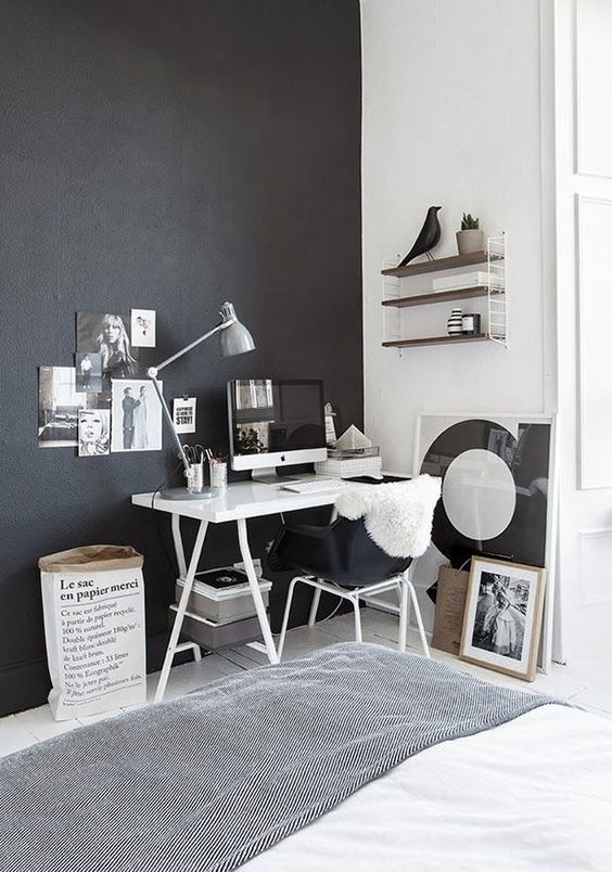 the home office nook is defined by a black wall and a matching chair to visually separate it
