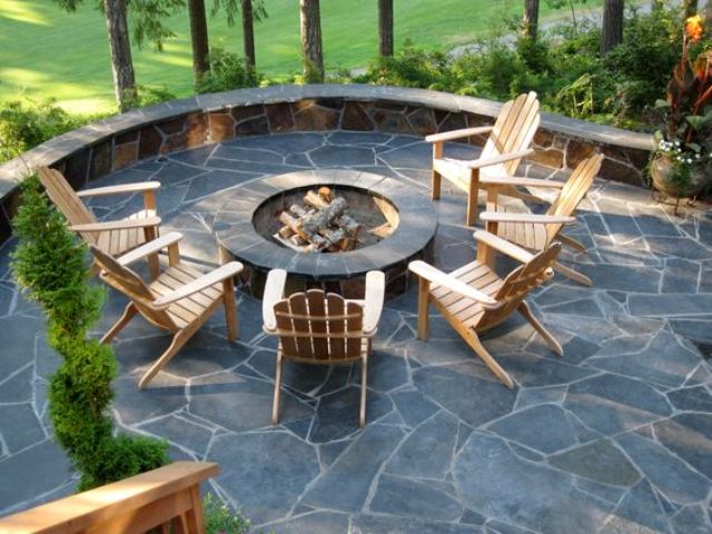 a stylish stone patio with a round firepit and simple wooden chairs to enjoy comfort