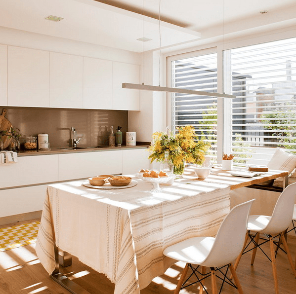 The kitchen features a sleek white kitchen with a brown backsplash, and a large window bring much light in