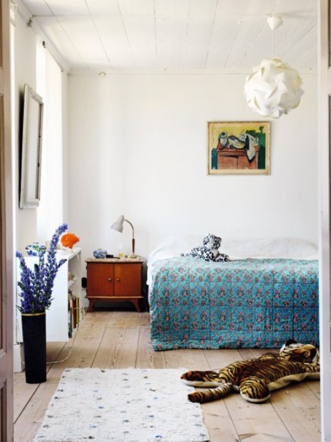 The master bedroom is done with mid century modern furniture, colorful printed textiles, artworks and accessories