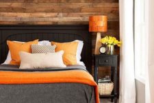 05 a cozy bedroom with a reclaimed wooden wall and bold orange accents that add a cheerful touch to the space